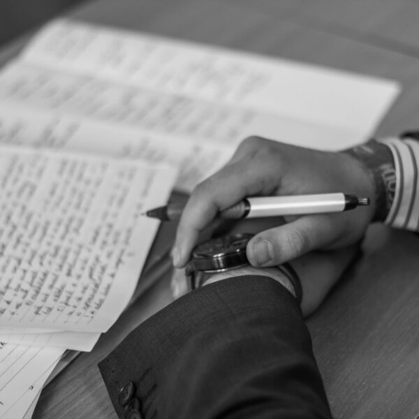 grayscale photography of person holding pen