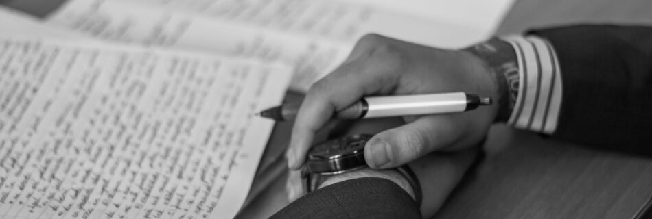 grayscale photography of person holding pen